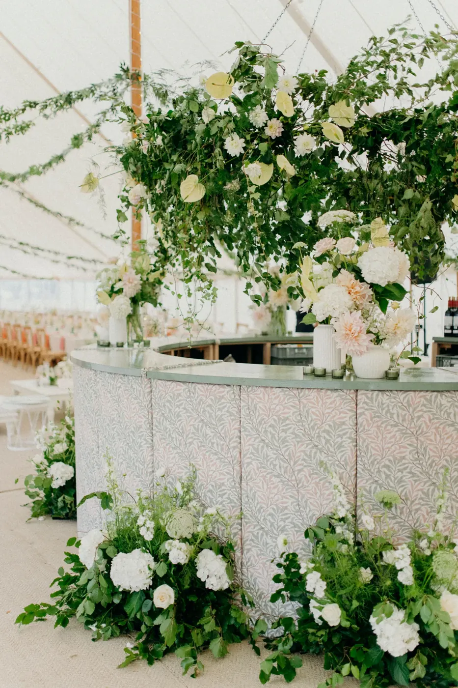 White and green floral installation around a marquee bar by Studio Lo